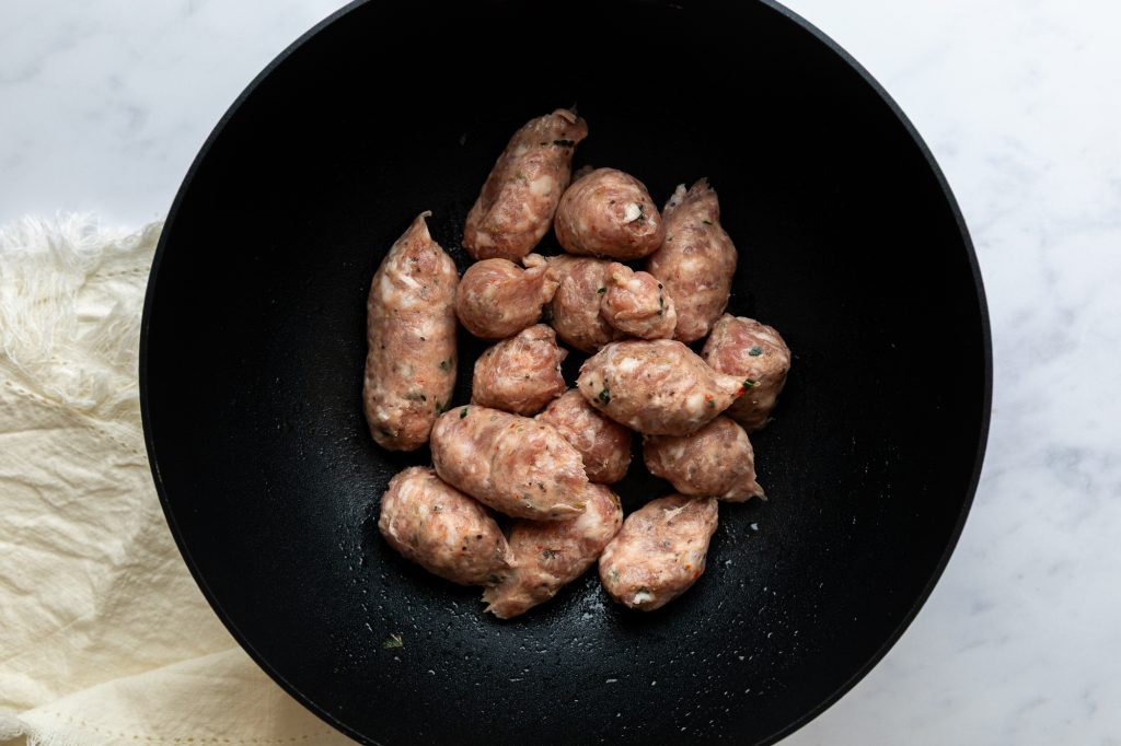 Sausage meat squeezed out of the skins into a large frying pan.