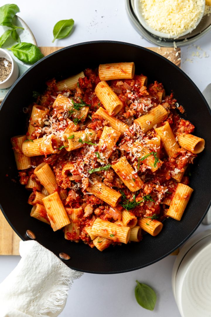 The cooked sausage ragu and pasta in a saucepan.