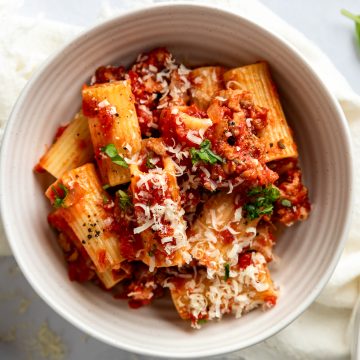 A white bowl of sausage and fennel pasta sprinkled with parmesan.