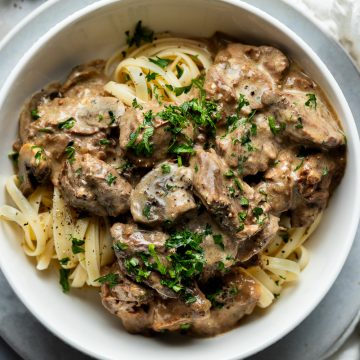 A bowl of beef stroganoff served on pasta.