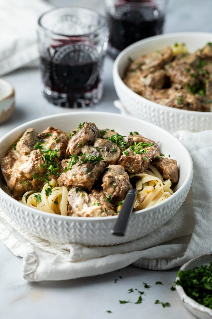Two bowls of beef stroganoff served with pasta.