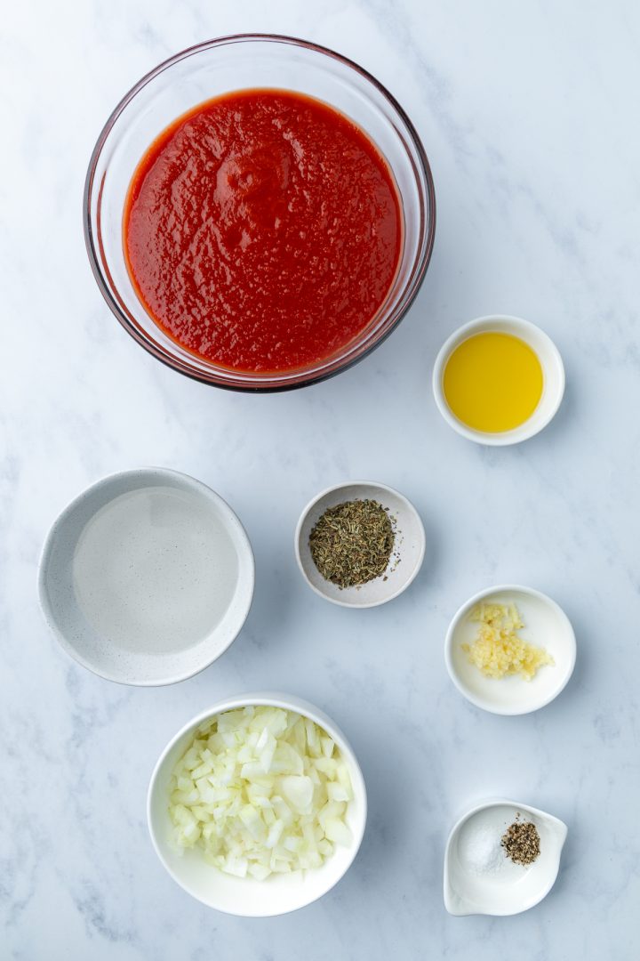 Ingredients needed to make the tomato sauce measured out in to bowls.