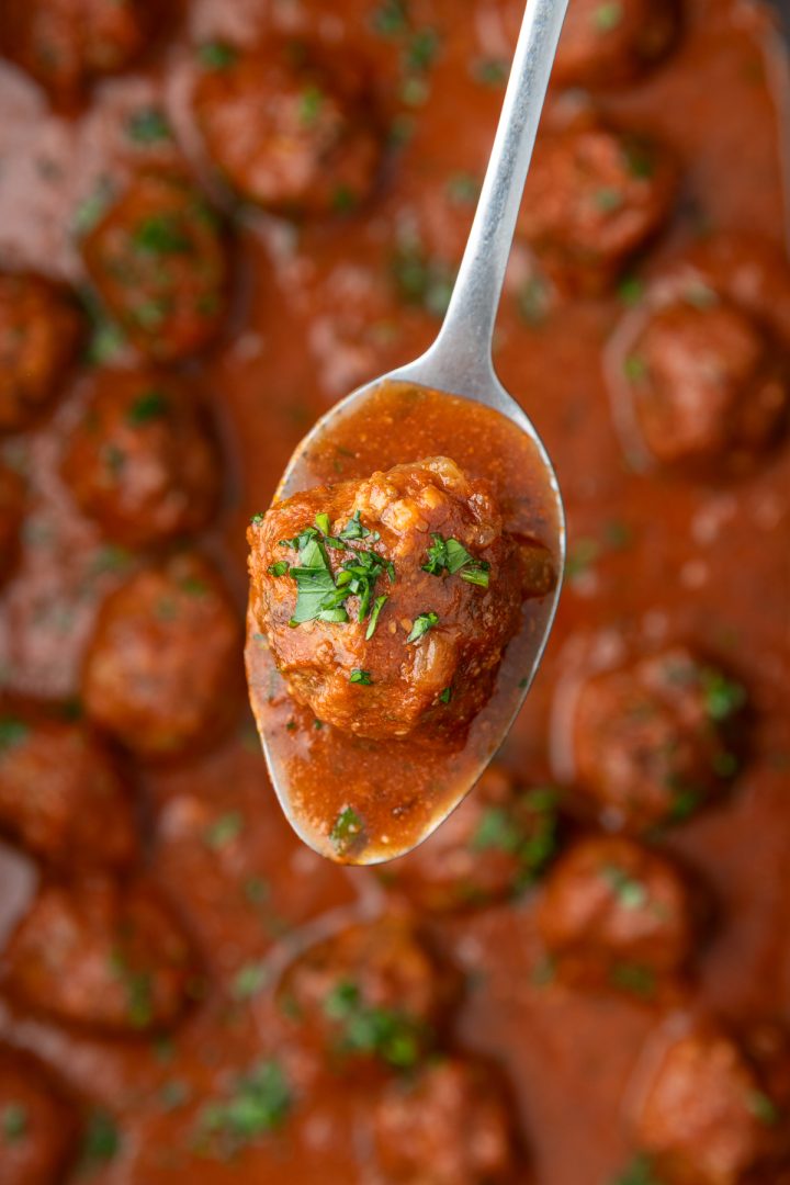 A spoon holding up a slow cooked meatball.