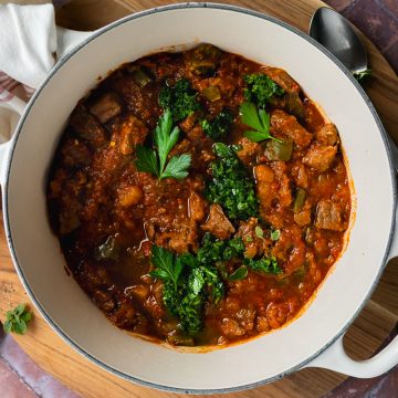 A pan of butternut and beef stew topped with chimichurri.