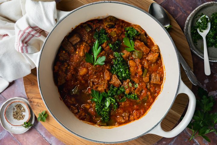 A pan of butternut and beef stew topped with chimichurri.