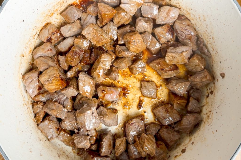 The browned beef in a saucepan.