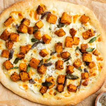 A whole roasted butternut squash pizza on brown paper.