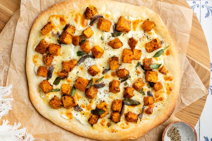 A whole roasted butternut squash pizza on brown paper.