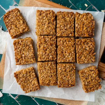 Flapjacks cut into bars, arranged on white baking paper.