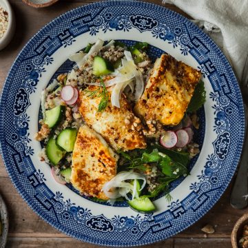 A plate of halloumi quinoa salad, with extra lemon dressing to the side.