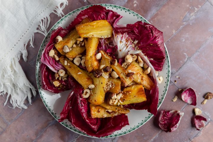 Parsnip salad on a plate with small radicchio leaves on the background to the right hand side.
