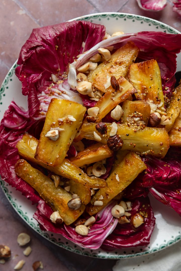 Close up of the roasted parsnips topped with chopped hazelnuts.