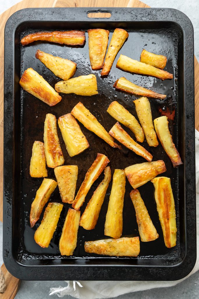 The roasted parsnips on a baking tray fresh from the oven.
