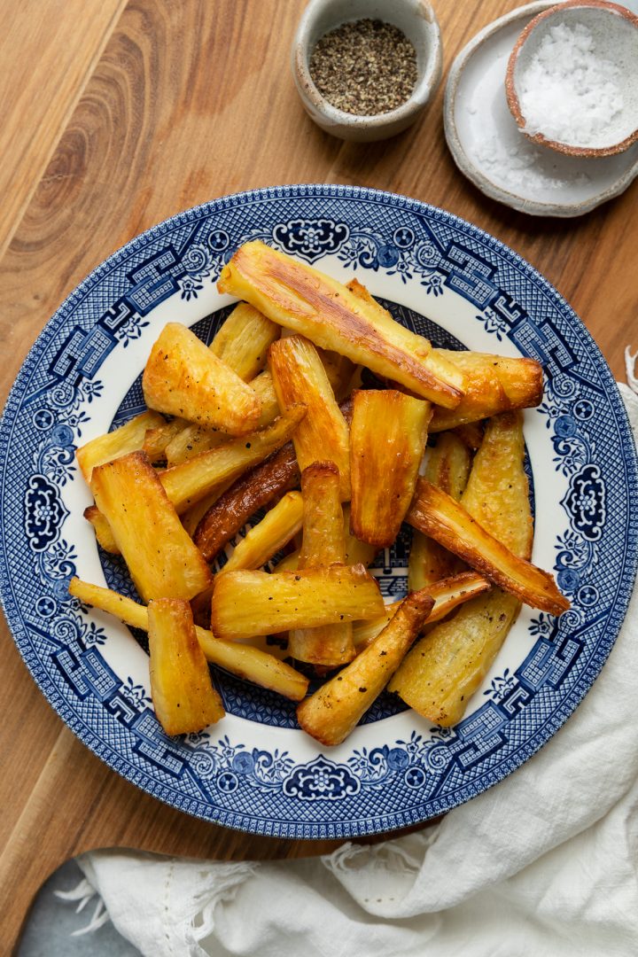 A plate of roasted parsnips with salt and black pepper ready to serve.