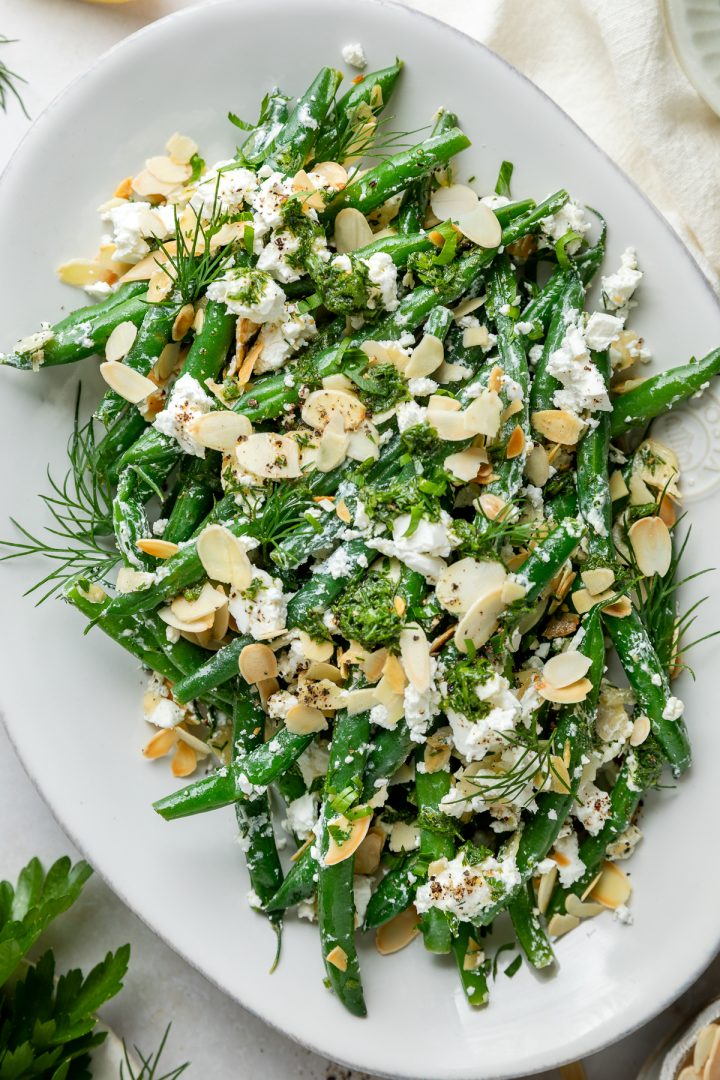Close up of a plate of green beans with feta and almonds.