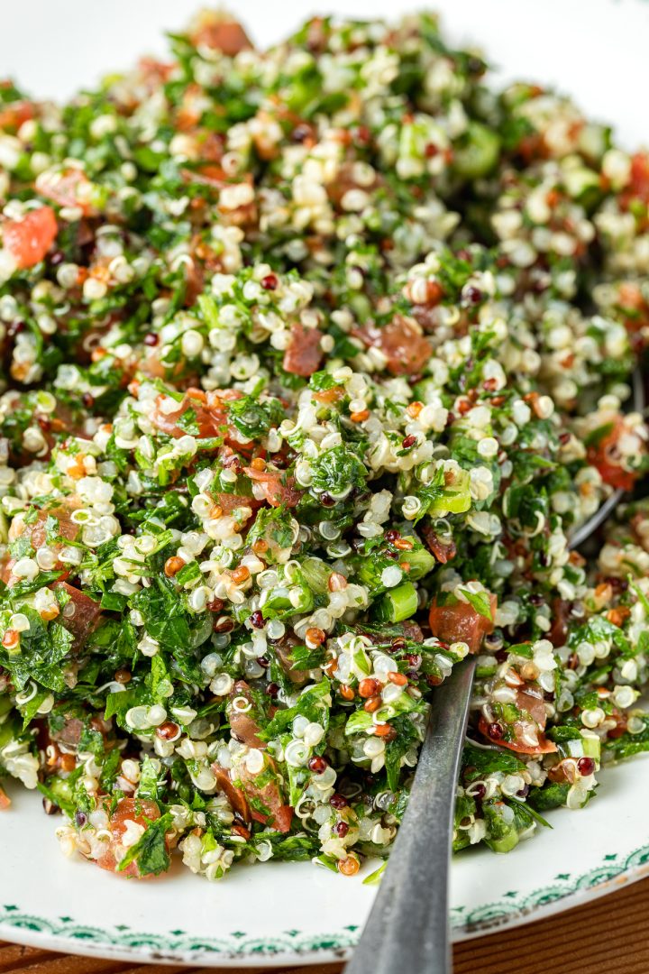 Close up side view of a pile of the quinoa parsley salad on a plate with a spoon ready to serve.