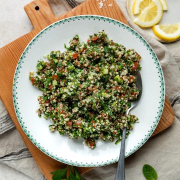 A bowl of quinoa tabouleh with a spoon ready to serve.