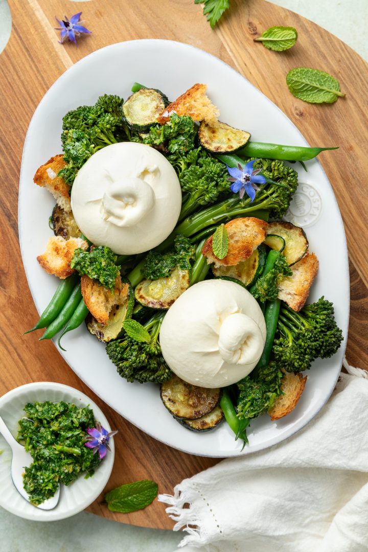 Two balls of burrata placed on the cooked vegetables and croutons.