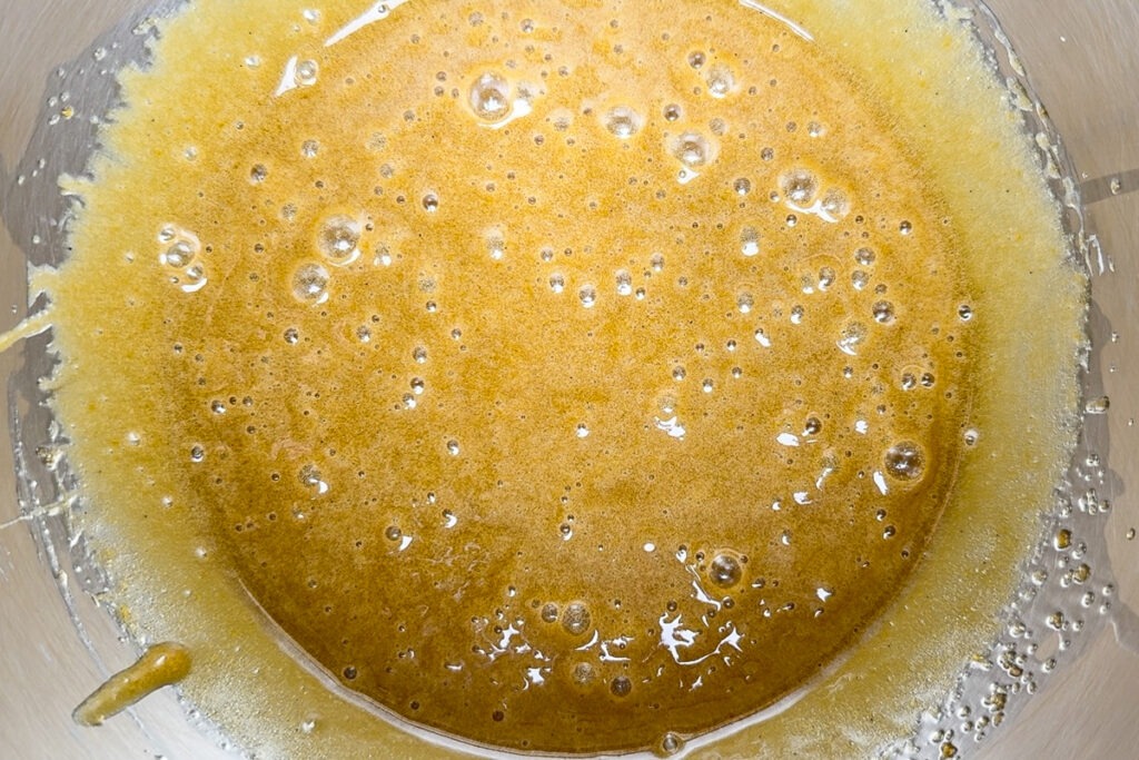 The whisked eggs, oil and sugar in a bowl.