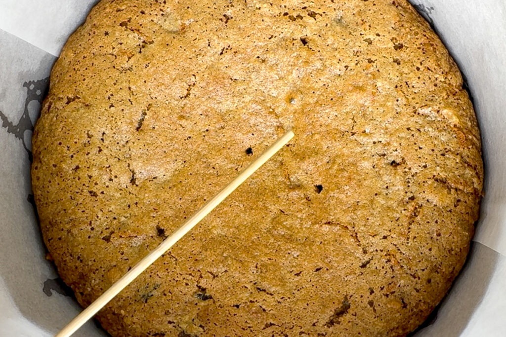 Close up of a wooden skewer showing that is has come out of the cake clean, with no crumbs on it.