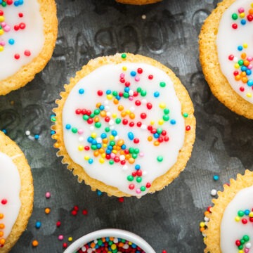 Overhead photo of iced fairy cakes on a metal baking tray.