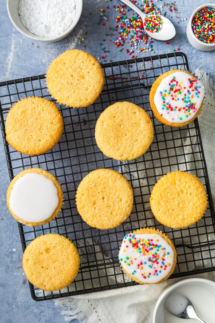 Fairy cakes on a wire cooling rack, some iced, others left plain.