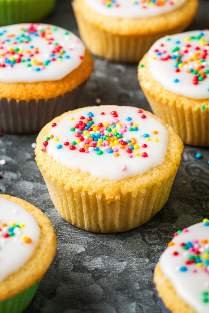 Close up side view of iced fairy cake in a paper case.