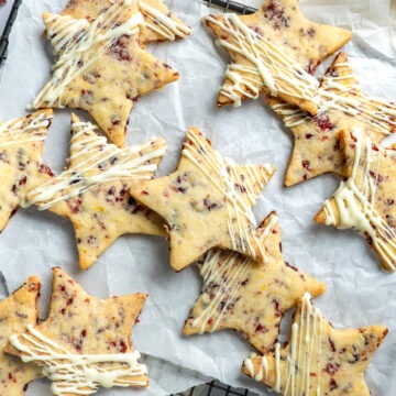 Overhead photo of shortbread stays on a cooling rack, with dried cranberries scattered around them.