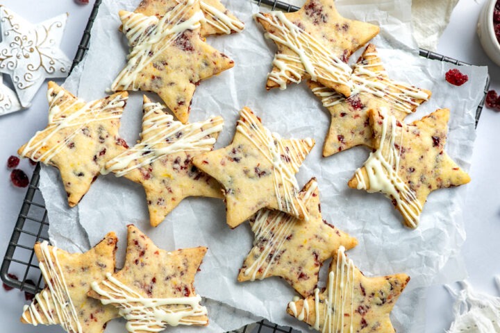 Overhead photo of shortbread stays on a cooling rack, with dried cranberries scattered around them.