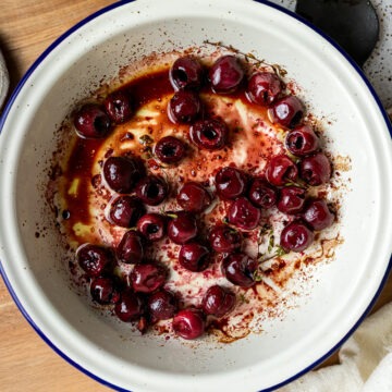 Roasted cherries in a round enamel dish.