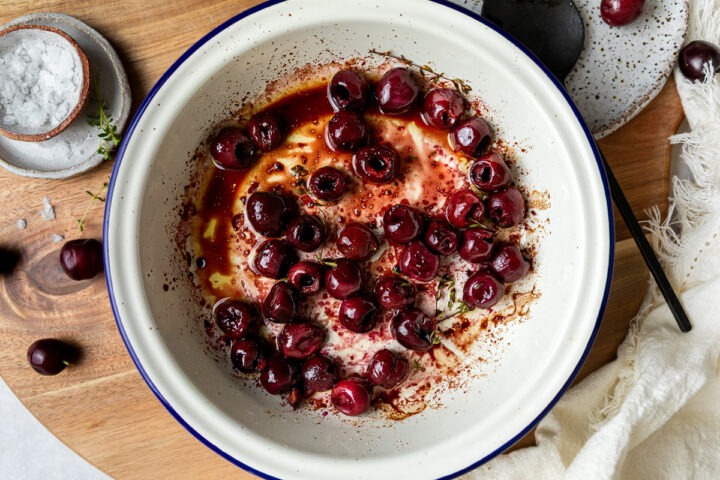 Roasted cherries in a round enamel dish.