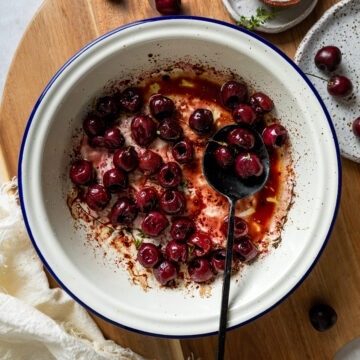 A bowl of roasted cherries with a spoon ready to serve.