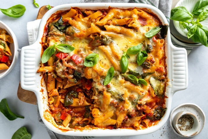 A dish of freshly baked sausage pasta bake topped with cheese.