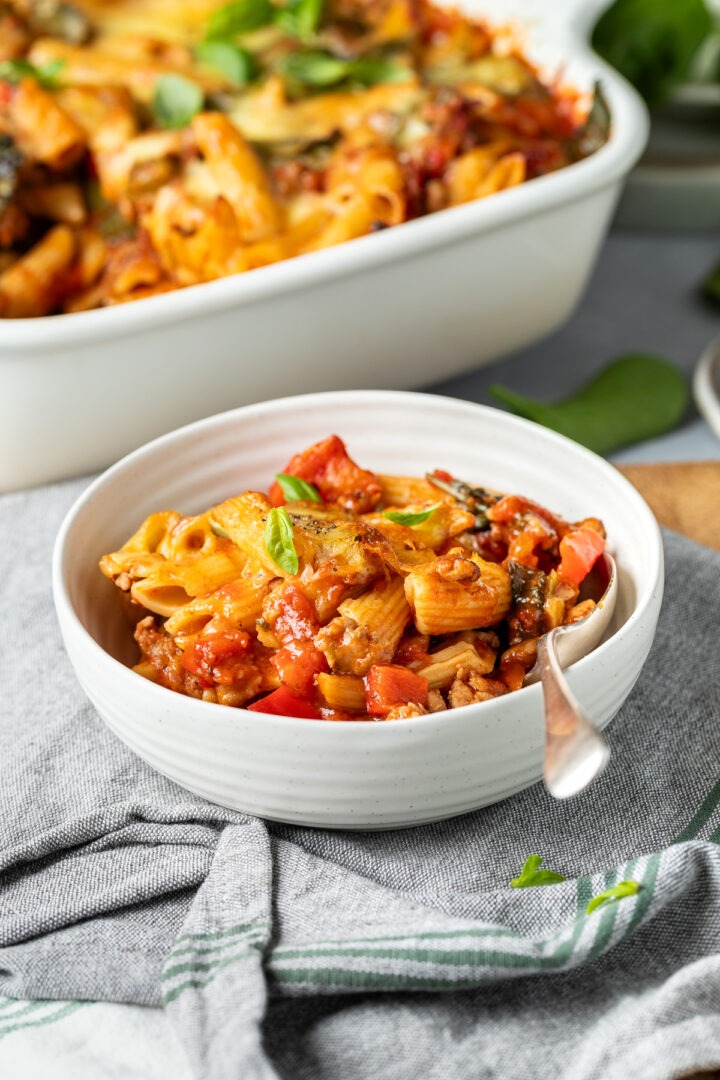 A bowl of the sausage pasta bake with a spoon in ready to eat.