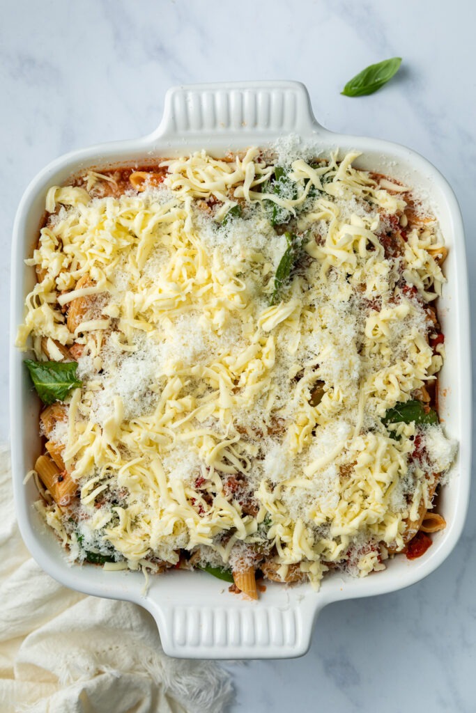 Cheeses sprinkled over the pasta bake, ready for the oven.