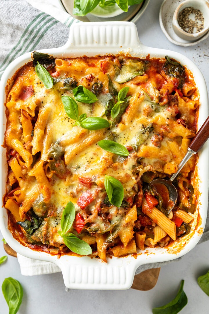 Overhead photo of sausage pasta bake with a spoon in it ready to take a portion of pasta out.