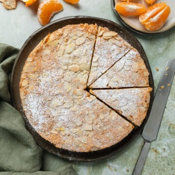 Mandarin almond cake dusted with icing sugar, cut into slices.