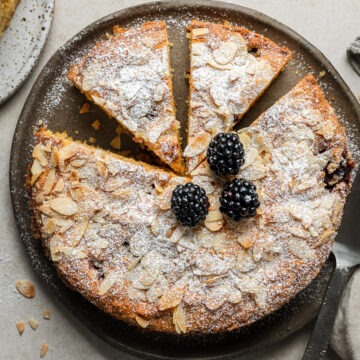 Homemade lemon blackberry cake topped with icing sugar and fresh blackberries.