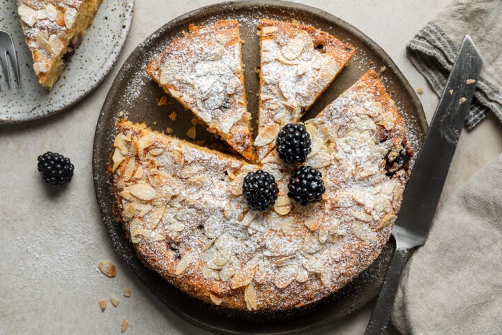 Homemade lemon blackberry cake topped with icing sugar and fresh blackberries.