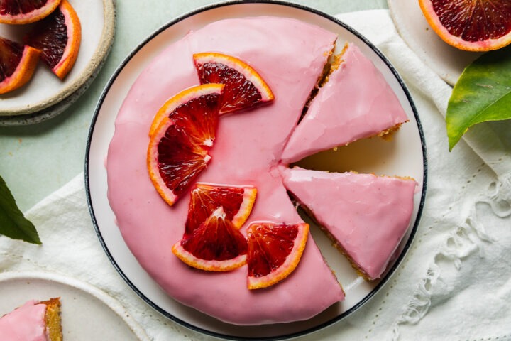 Overhead photo of homemade blood orange and almond cake topped with blood orange icing.