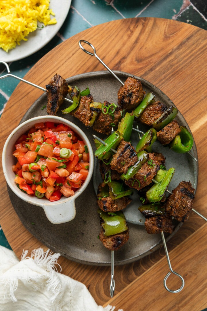 A plate of 4 homemade Spanish beef skewers served with capsicum salsa.